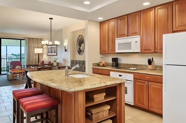 A modern kitchen with granite countertops, wooden cabinets, and a built-in microwave.