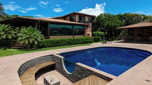 Une maison moderne avec une piscine, entourée d’un jardin bien entretenu et de palmiers.