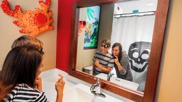 A bathroom with a large mirror, a sink, and a red wall decoration.
