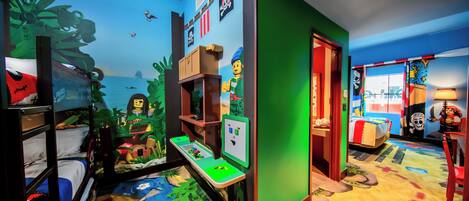 Quarto com beliches, área de recreação e um mural de um navio pirata.