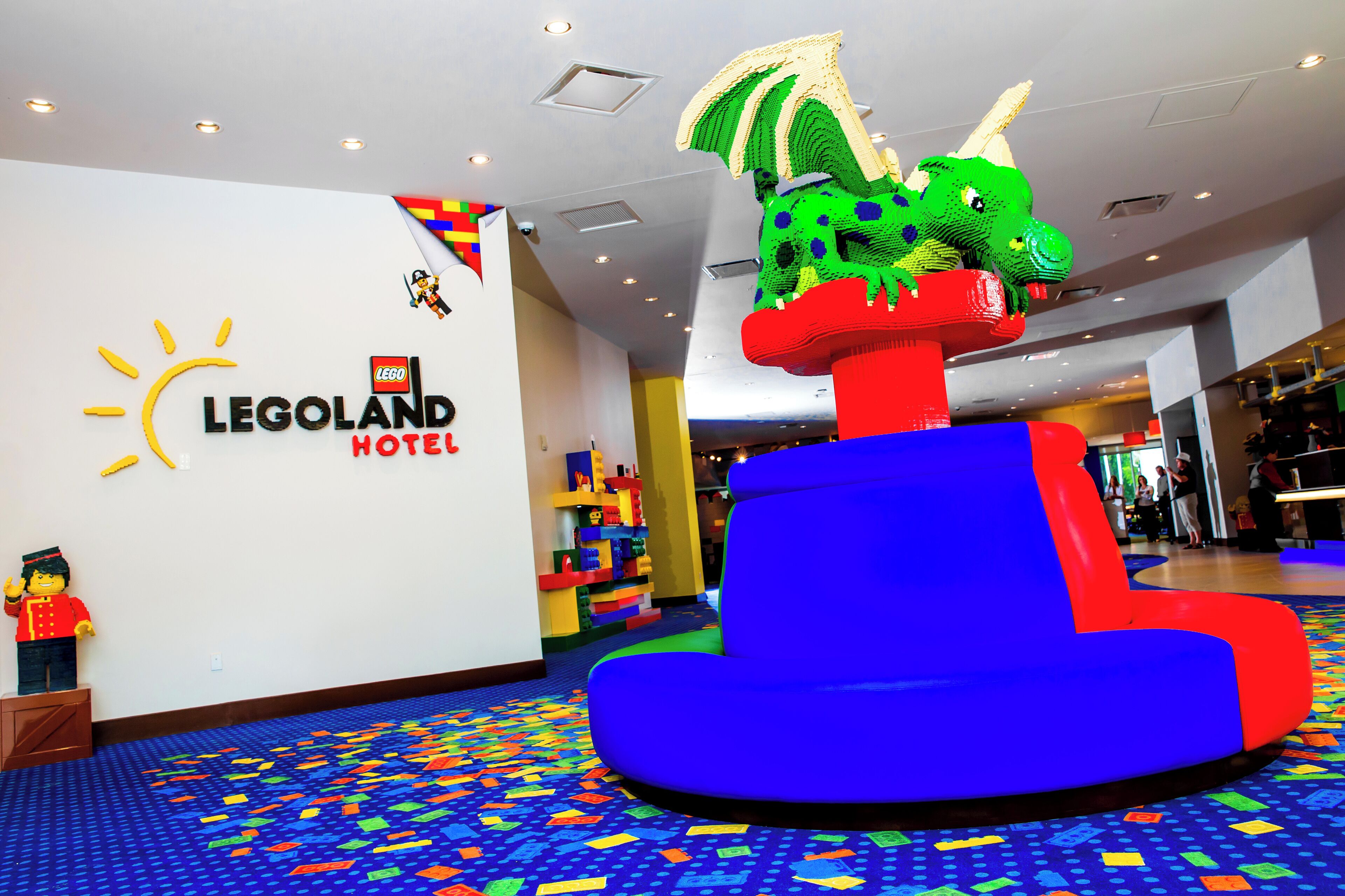 Vestíbulo de un hotel con temática LEGO, con una zona de juegos colorida, una figura de LEGO de un soldado y una decoración de LEGO con forma de dragón.
