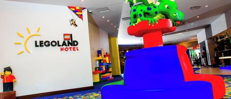 Vestíbulo de un hotel con temática LEGO, con una zona de juegos colorida, una figura de LEGO de un soldado y una decoración de LEGO con forma de dragón.
