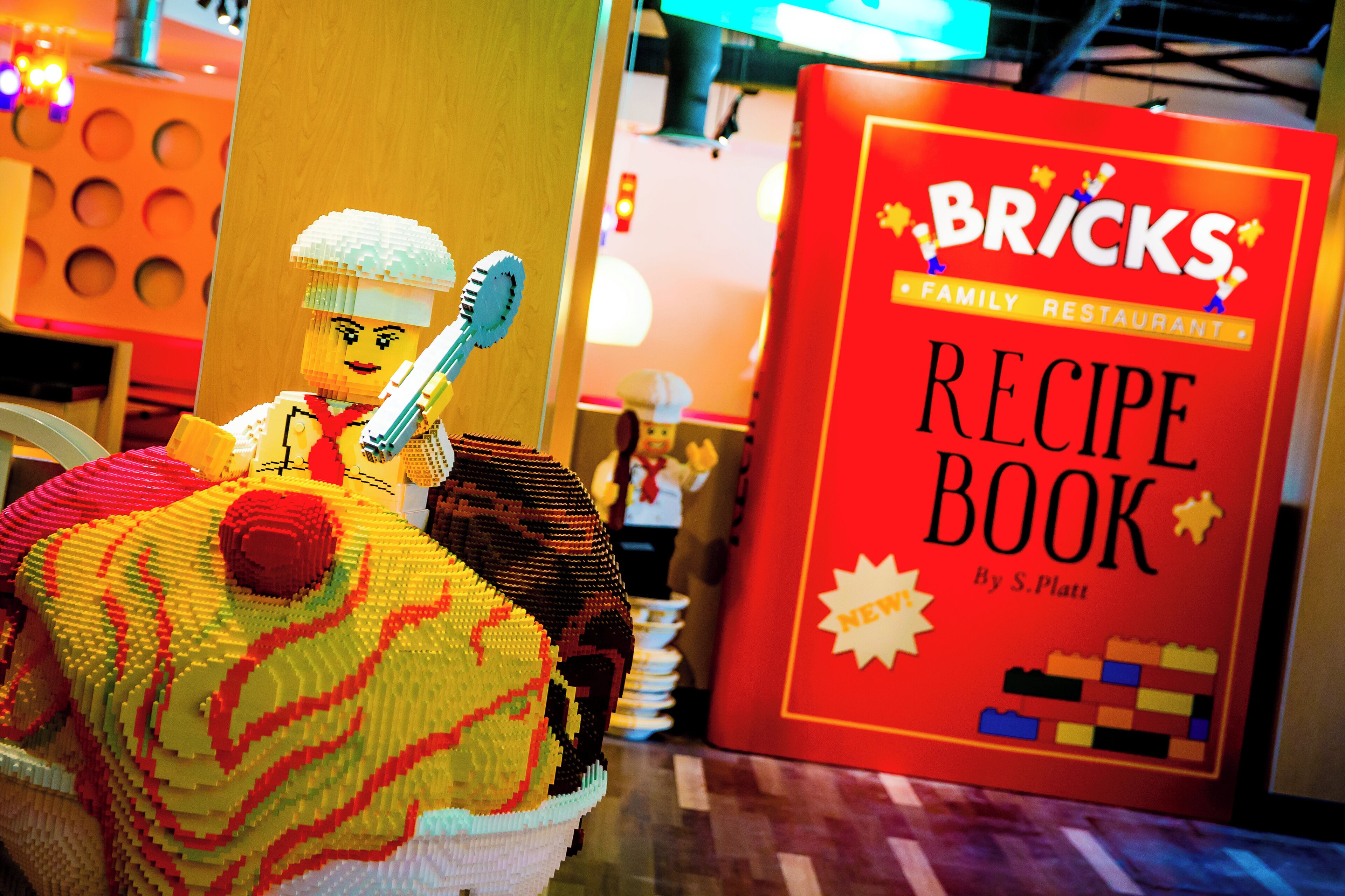 A LEGO chef with a recipe book titled "BRICKS Family Restaurant" by S. Platt.