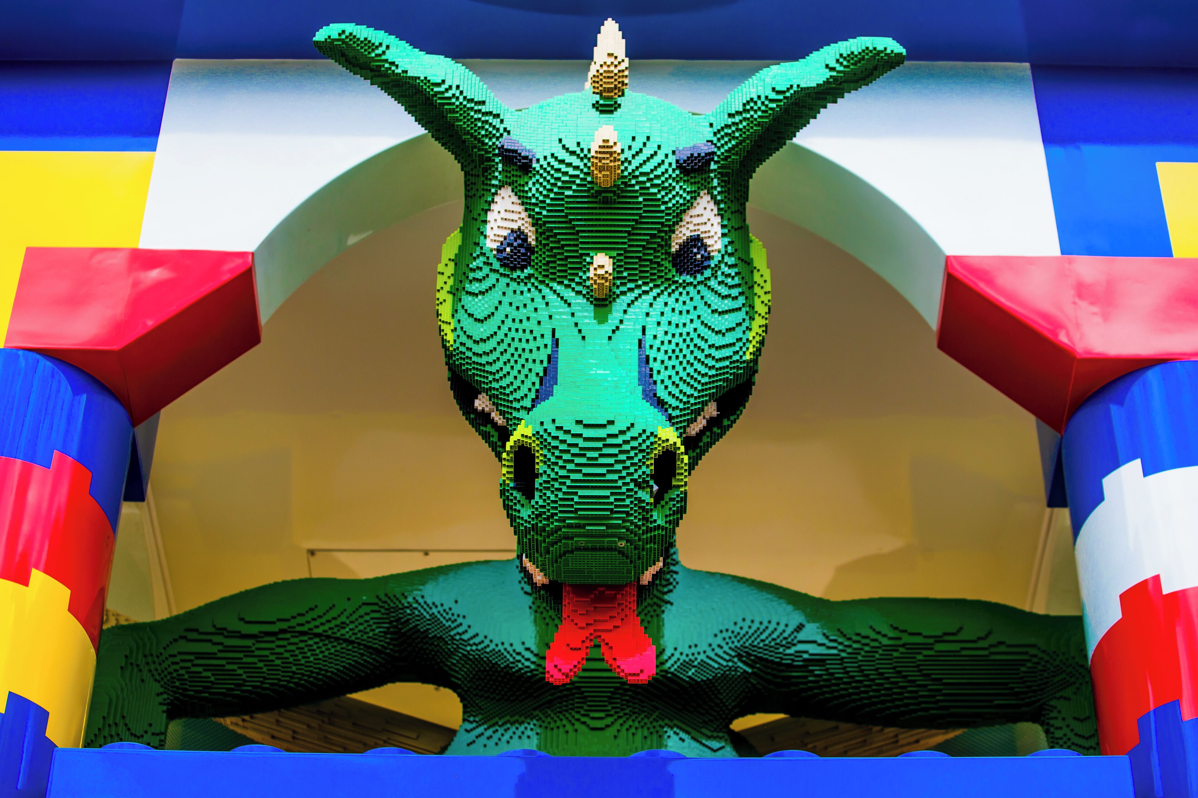 A LEGO sculpture of a dinosaur in a colorful, geometric setting.