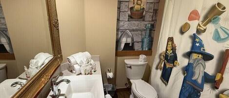 A bathroom with a large mirror, a sink, a toilet, and a shower curtain with cartoon characters.