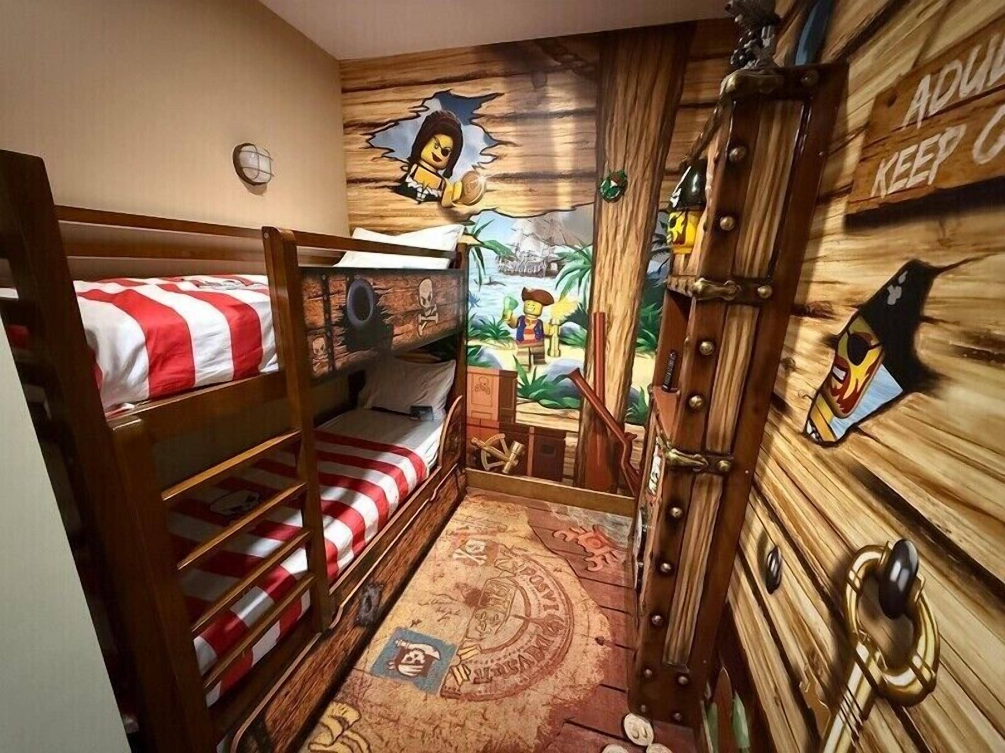 A room with bunk beds, a mural, and a wooden door with a sign.