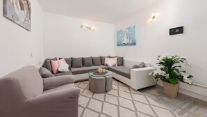 Een moderne woonkamer met een grijze modulaire bank, een glazen salontafel en een kamerplant.