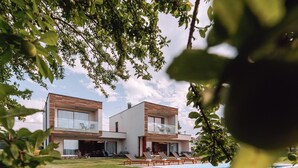 Une maison moderne à deux étages avec une piscine, entourée de verdure.