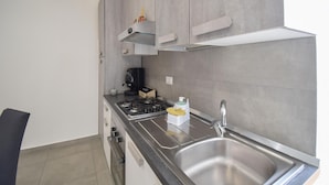 Una cocina moderna con gabinetes grises, un lavamanos de acero inoxidable, una cafetera y una estufa a gas.