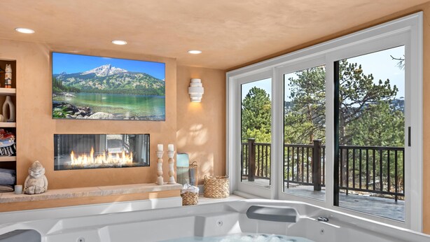 Un espacio de spa con un jacuzzi, una chimenea y un amplio ventanal con vistas a la montaña.