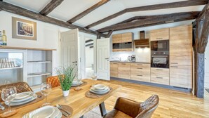 A modern kitchen with wooden cabinets and a dining area with a wooden table set for four.