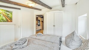 A bedroom with a bed, a wardrobe, and a view of a kitchen.