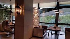 Un intérieur moderne avec un mur d’accent en pierre, un coin salon avec un canapé et des fauteuils, et un éclairage suspendu.