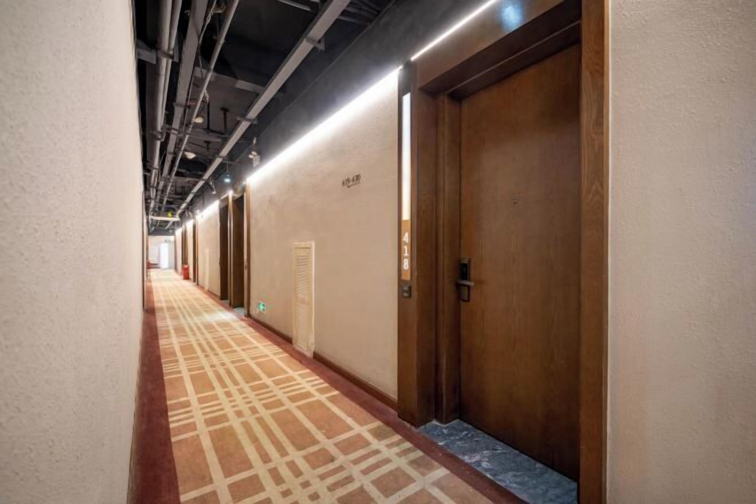 A hotel corridor with wooden doors, a patterned carpet, and a sign indicating room number 418.