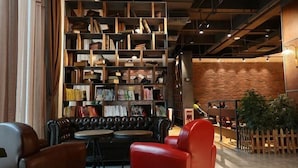 Un coin lecture accueillant avec des canapés en cuir, une bibliothèque en bois remplie de livres et un mur de briques en arrière-plan.
