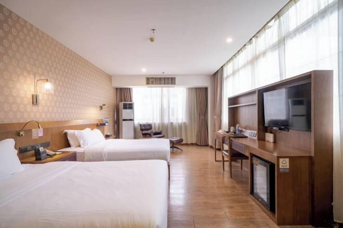 A hotel room with two beds, a desk, a television, and a minibar.
