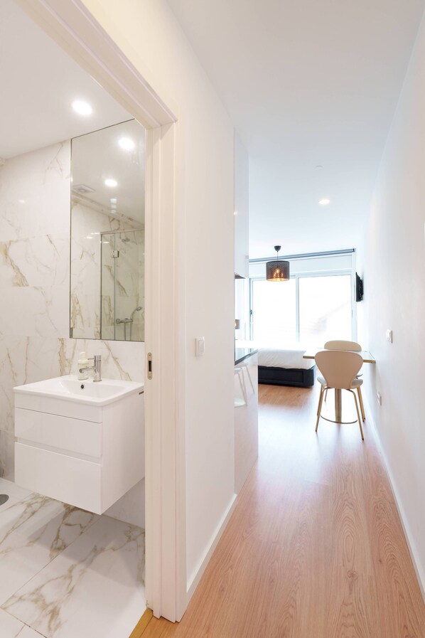 A modern bathroom with a marble vanity, a large mirror, and a shower.