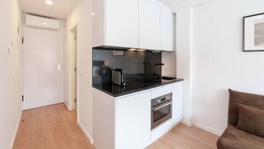 A compact kitchen with white cabinetry, a black countertop, and a built-in oven. - VIVA Bartolomeu Beach Flats 3E (Porto)