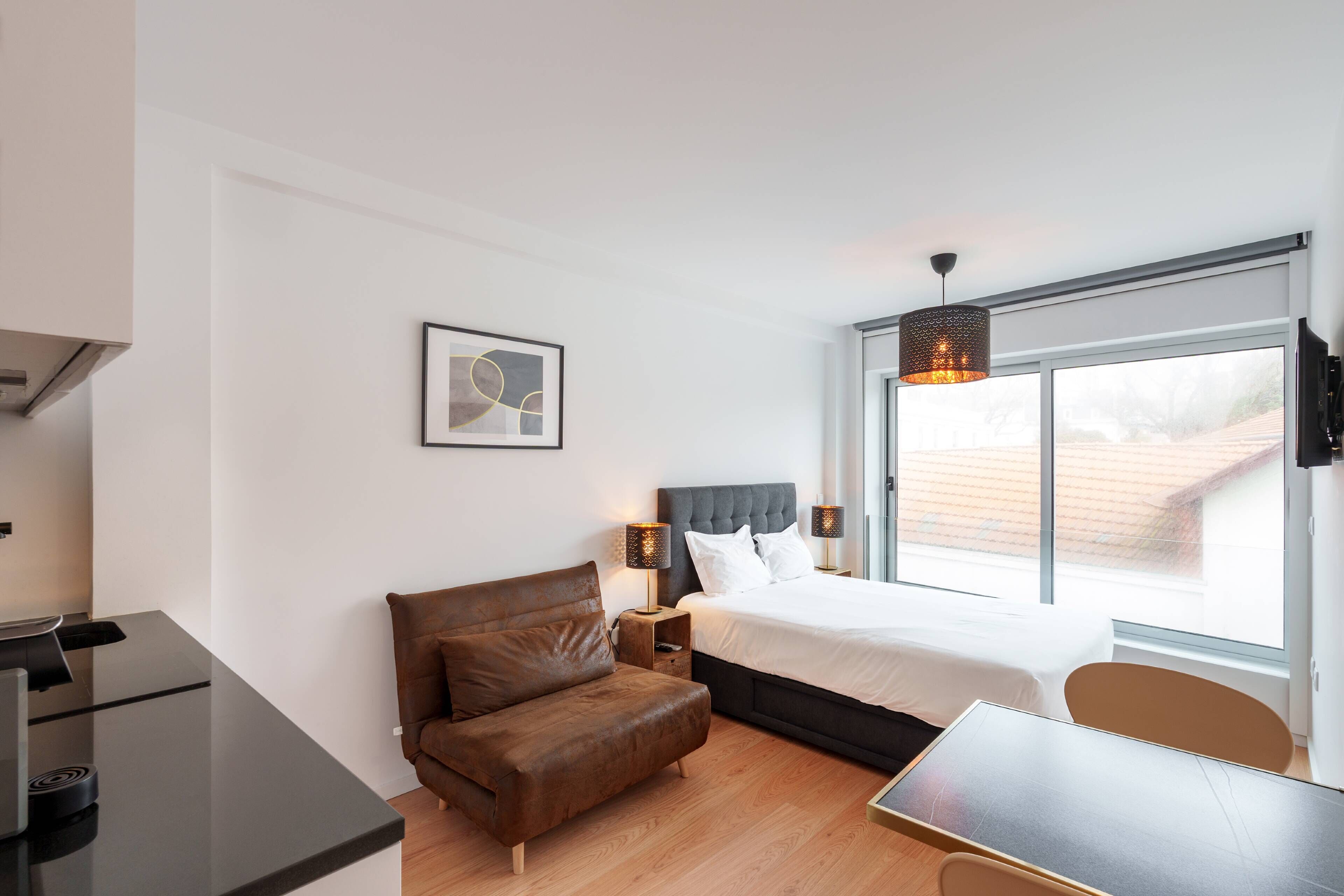 Ein modernes Hotelzimmer mit Bett, Schreibtisch, Stuhl und einem Fenster mit Blick.