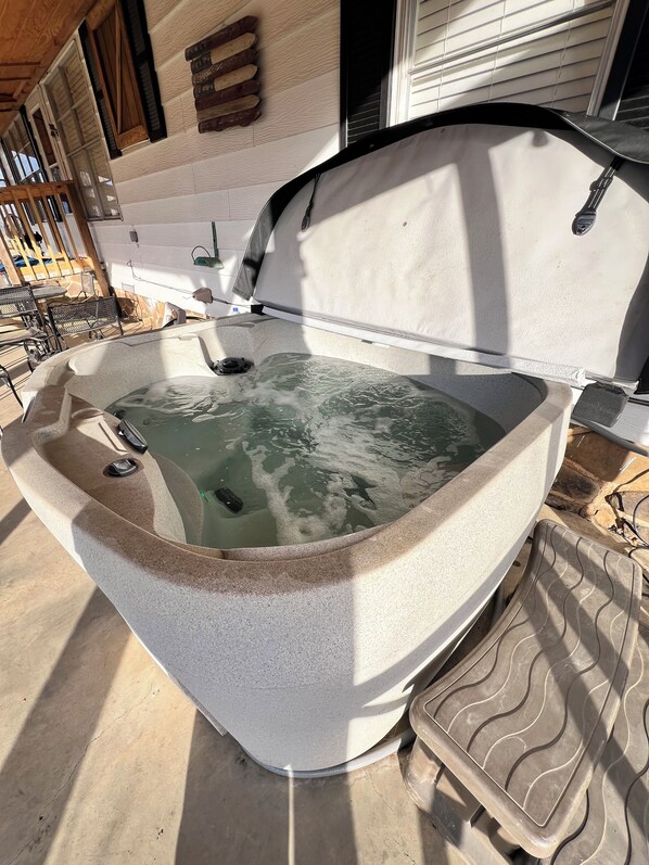 A hot tub with a stone exterior, a metal frame, and a tiled deck area.