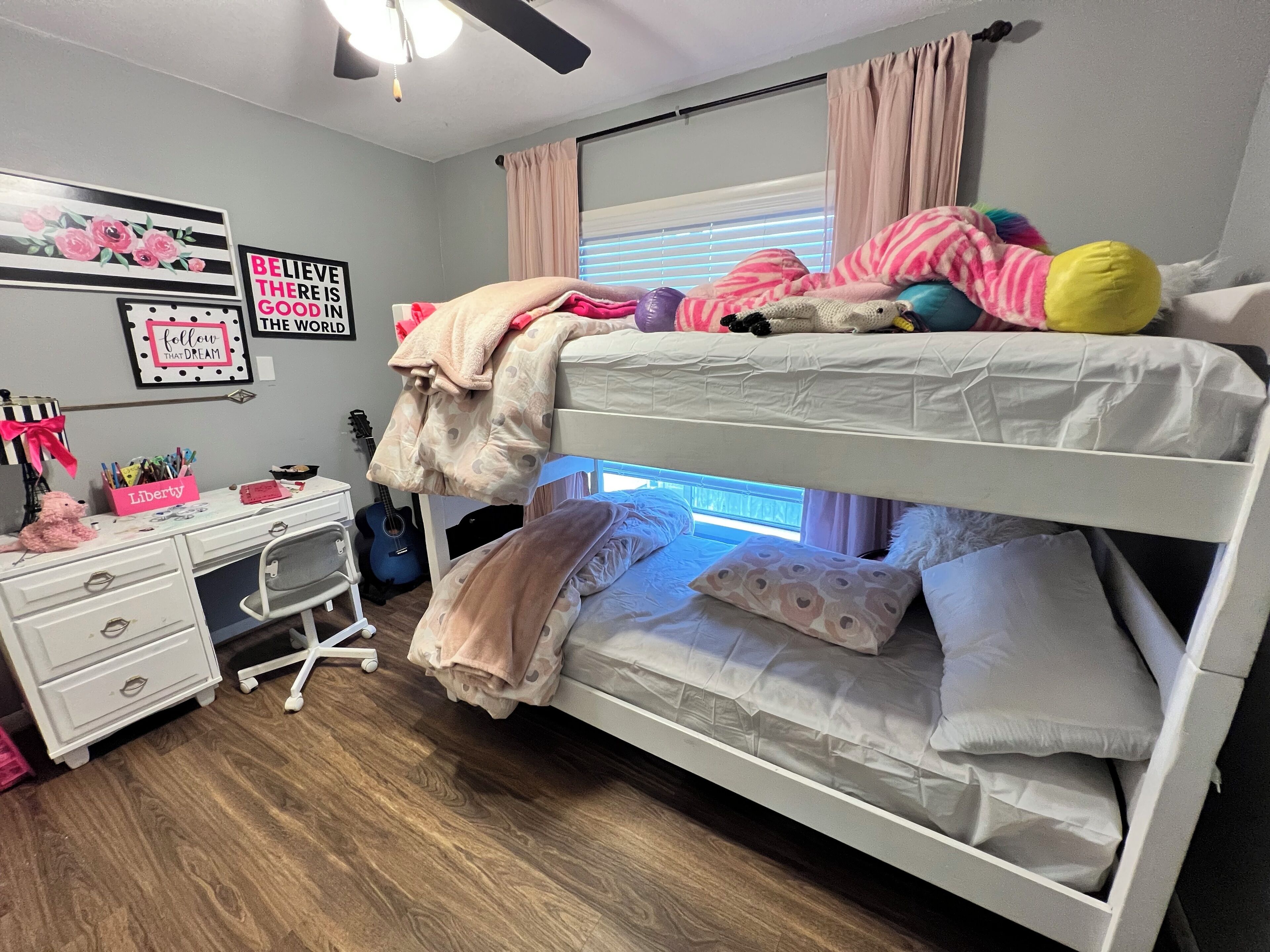 A bunk bed with a desk and chair, a guitar, and motivational posters.