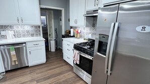 Una cocina moderna con gabinetes blancos, electrodomésticos de acero inoxidable y un salpicadero estampado.