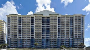 Un hôtel à plusieurs étages, doté de balcons, d’un toit plat et surplombant un ciel dégagé.