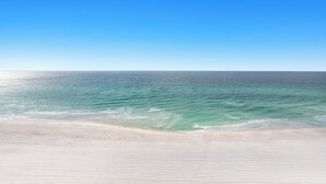 Une plage avec un ciel bleu dégagé et une mer calme.