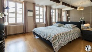 Quarto moderno com cama grande, mesas de cabeceira e um espelho.