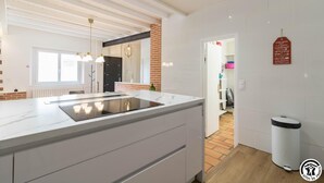 Cozinha moderna com uma ilha grande, armários brancos e parede de tijolos.