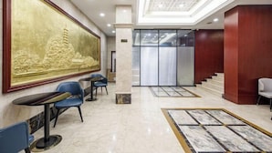 A hotel lobby with a large mural, marble flooring, and a staircase leading to an elevator. - Yayue Hotel (Zhenjiang Railway Station North Square Xijin Ferry Store) (Zhenjiang)