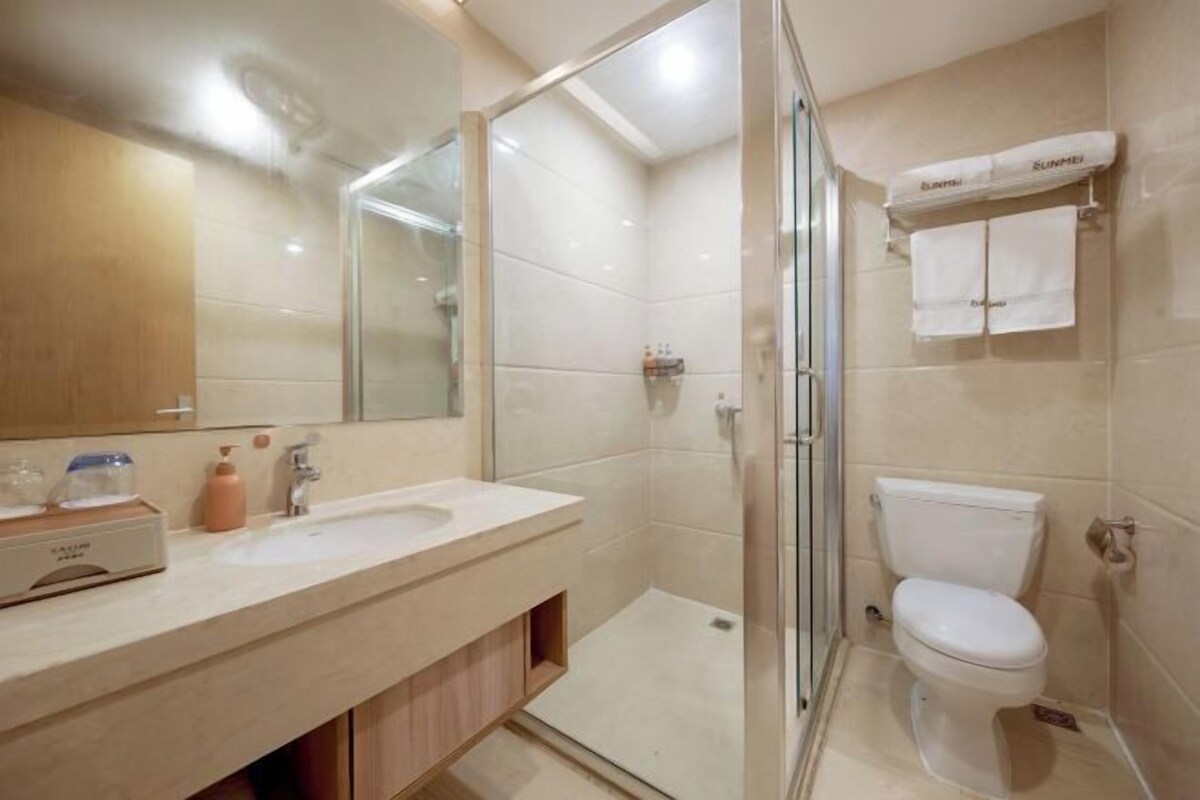 A modern bathroom with a glass-enclosed shower, a white toilet, and a vanity with a mirror and sink.