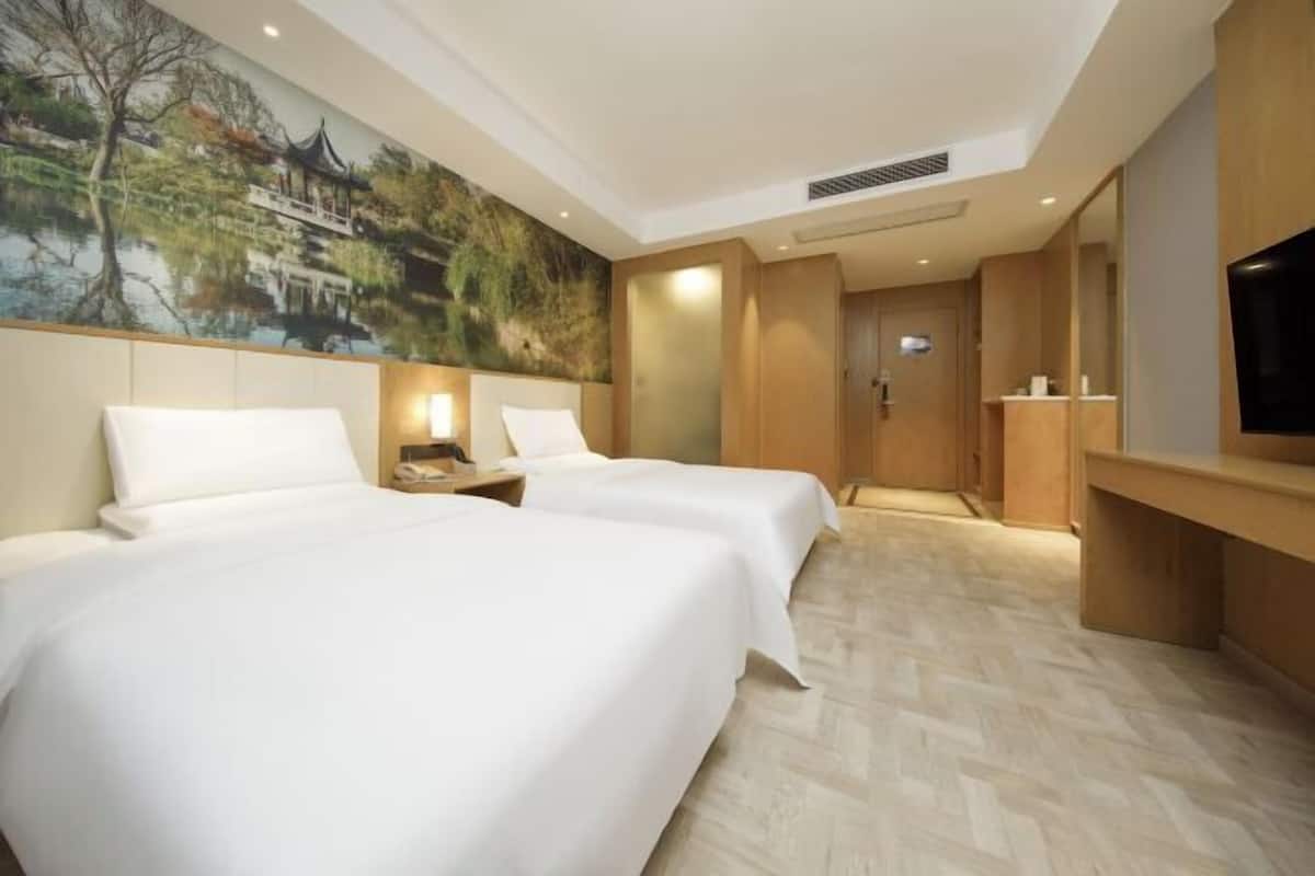 A hotel room with two beds, a TV, a painting of a traditional building, and a wooden cabinet.