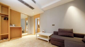 A modern living room with a sofa, a coffee table, and built-in wooden shelving. - Yayue Hotel (Zhenjiang Railway Station North Square Xijin Ferry Store) (Zhenjiang)