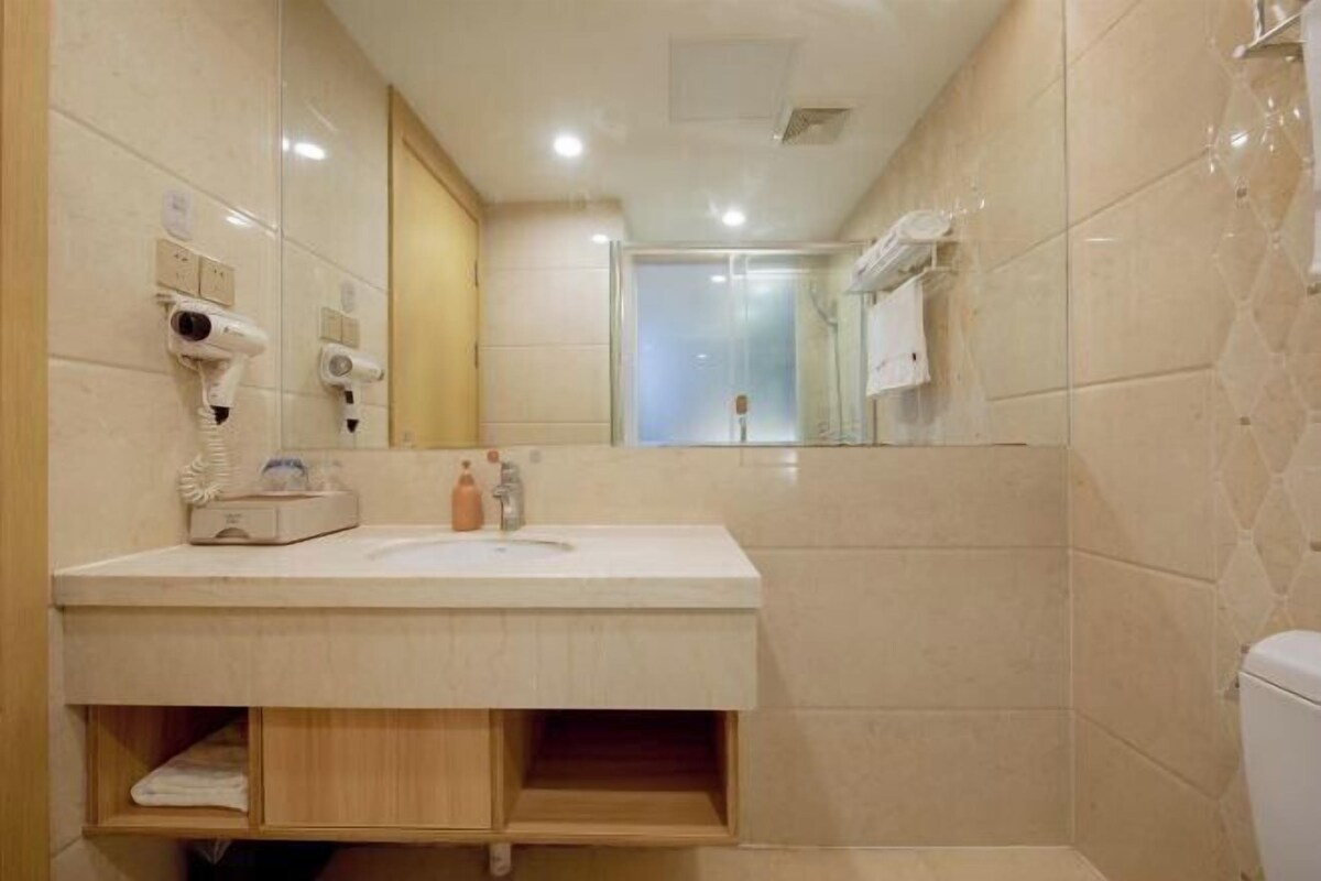 A bathroom with a sink, mirror, towel rack, and a shower area.