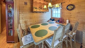 A wooden dining room with a large table and chairs, a built-in shelf with decorative items, and a window with curtains. - 2 bedroom pet friendly home in Rendalen (Rendalen)