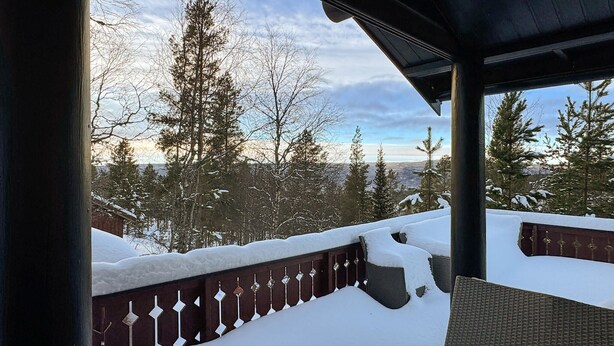 A snow-covered balcony with a wooden railing and a view of snow-covered trees and mountains. - 2 bedroom pet friendly home in Rendalen (Rendalen)