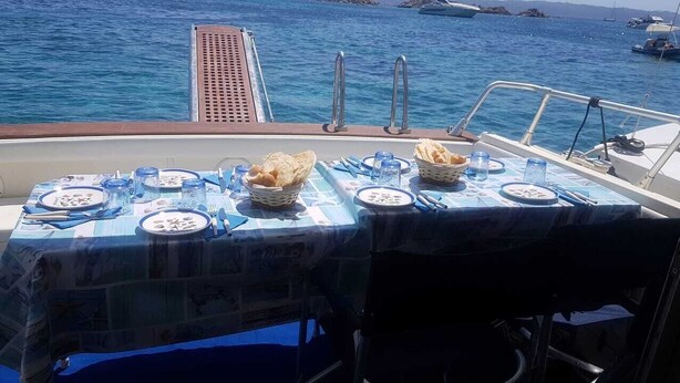 Mesa para dos personas con platos, cubiertos y pan en la cubierta de un barco.