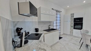 Una cocina moderna con armarios blancos, encimera negra y horno integrado.