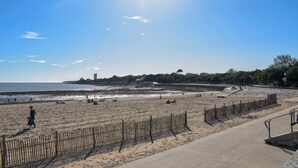 A beach with a wooden fence, a concrete walkway, and a clear sky.