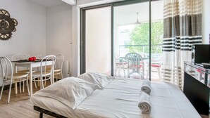 A bedroom with a bed, a table with chairs, and a view of the outdoors through a sliding door.