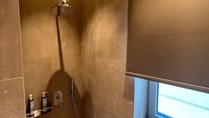 Un baño moderno con ducha, ventana y un perchero con artículos de aseo.