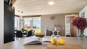 Een moderne keuken met een houten aanrecht, een fruitschaal, een boek en een vaas met bloemen.