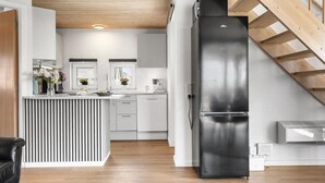 Een moderne keuken met een centraal eiland, roestvrijstalen apparatuur en een houten trap.