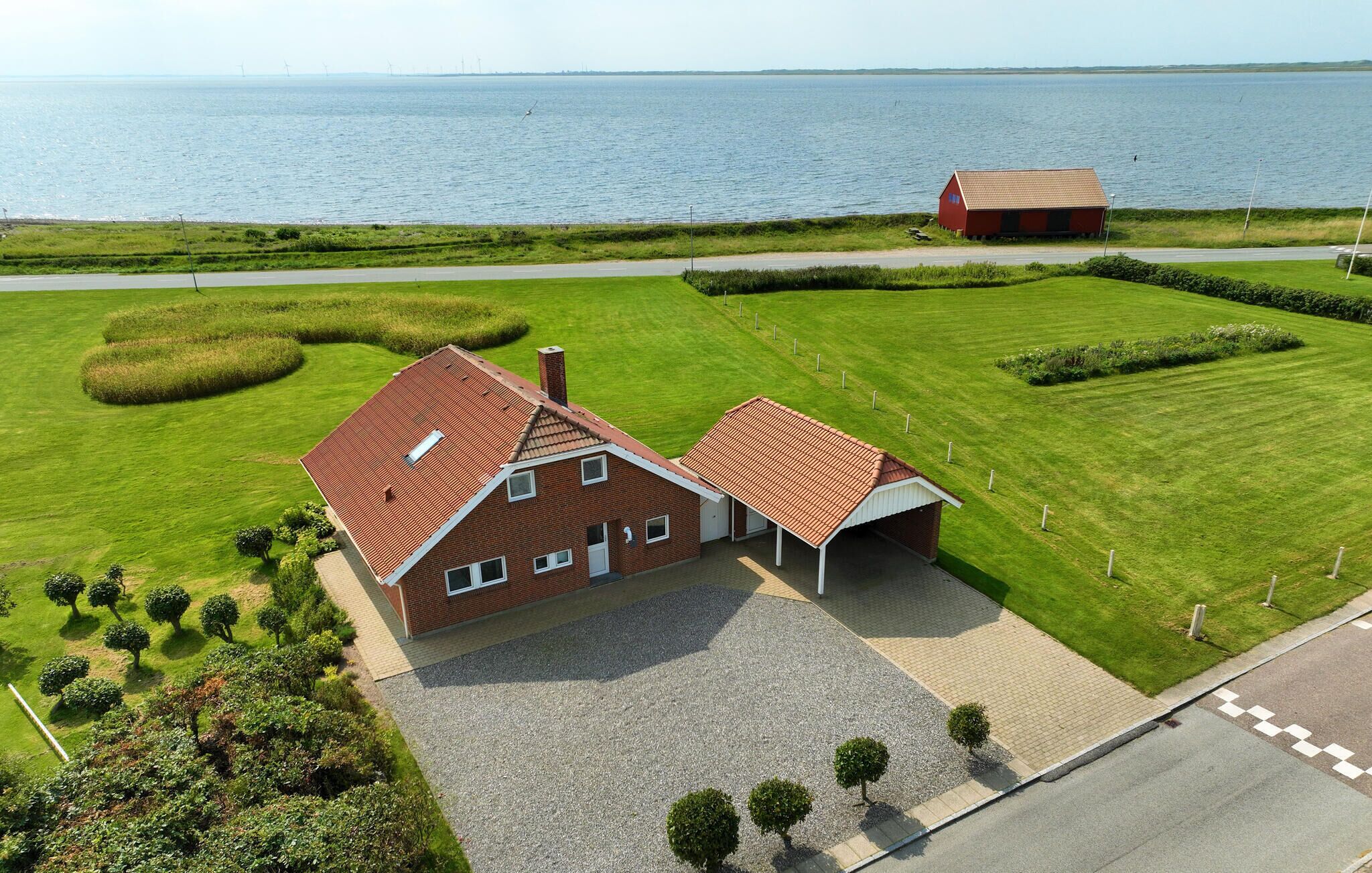 Een huis met twee verdiepingen, voorzien van een rode dakbedekking, een oprit en een verzorgd gazon.