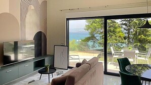 A modern living room with a sofa, a TV, and a dining area with a table and chairs.