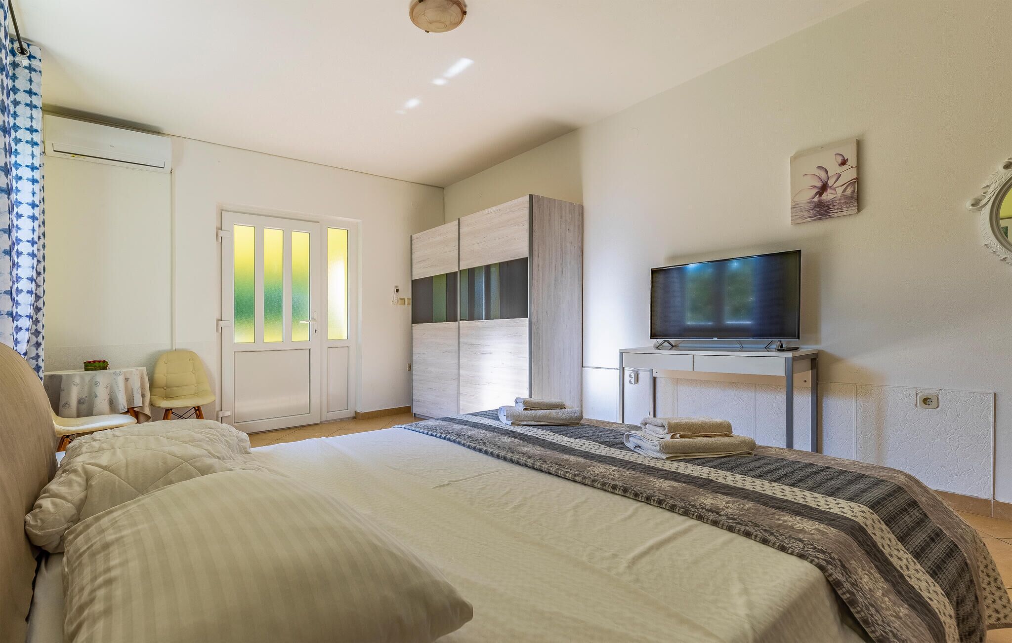 A bedroom with a bed, a TV, a wardrobe, and a chair.