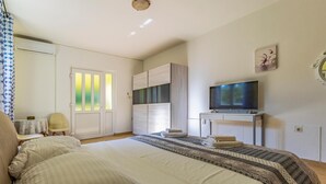 Ein Schlafzimmer mit Bett, Fernseher, Kleiderschrank und Stuhl.