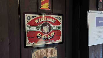A wall with vintage barber shop signs, including 'Williams' Barbers Favorite Soap' and 'Rarborough Classics'.