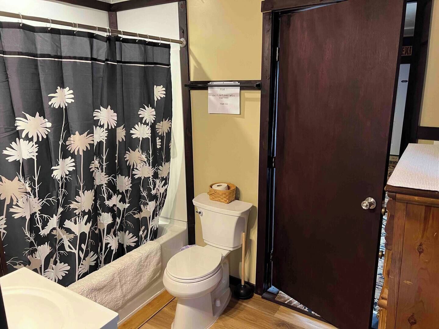 Une salle de bain équipée de toilettes, d’une baignoire et d’un rideau de douche orné d’un motif floral.